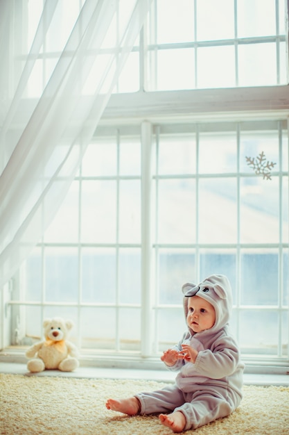 Foto grátis belo menino sentado à beira da janela
