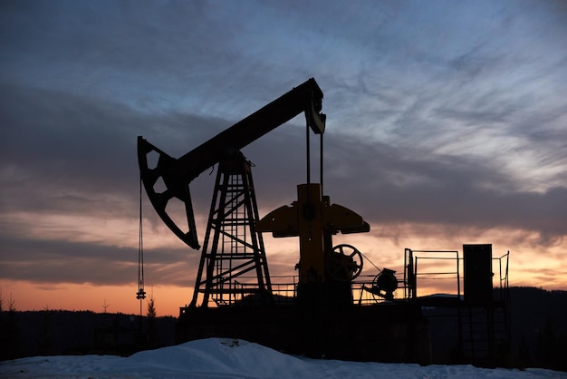 Belo pôr do sol sobre o campo petrolífero com jack de bomba