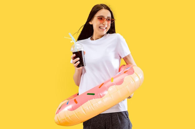 Foto grátis belo retrato feminino de meio comprimento isolado no fundo amarelo do estúdio. jovem mulher sorridente. expressão facial, verão, fim de semana, conceito de resort. cores da moda.