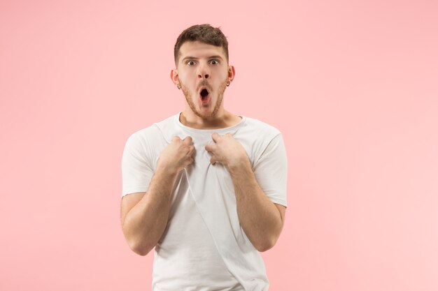 Belo retrato masculino com metade do comprimento isolado no estúdio rosa backgroud. O jovem emocionado surpreso