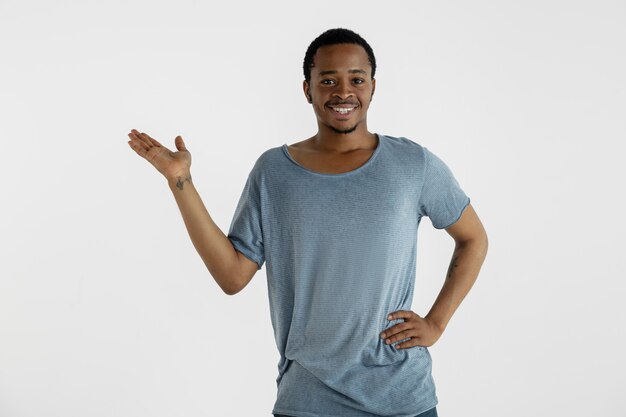 Belo retrato masculino em fundo branco. Jovem emocional afro-americano de camisa azul.