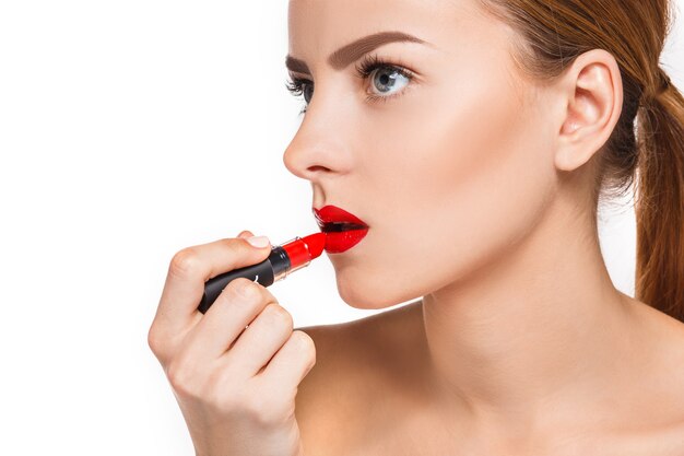 Belos lábios femininos com maquiagem e pomada vermelha em branco. Processo de trabalho do maquiador