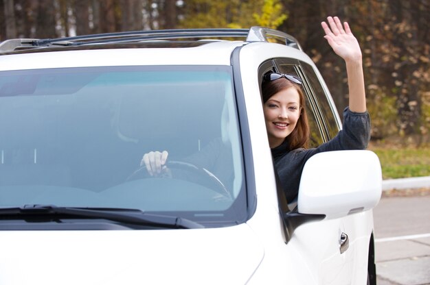 Foto grátis bem-sucedida bela jovem feliz em um carro novo - ao ar livre