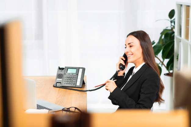 Bem sucedida jovem empresária falando no telefone com lápis na mão