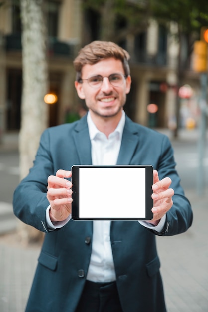 Bem sucedido jovem empresário mostrando tablet digital com tela branca