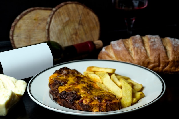 Bife coberto com queijo derretido, servido com batata frita