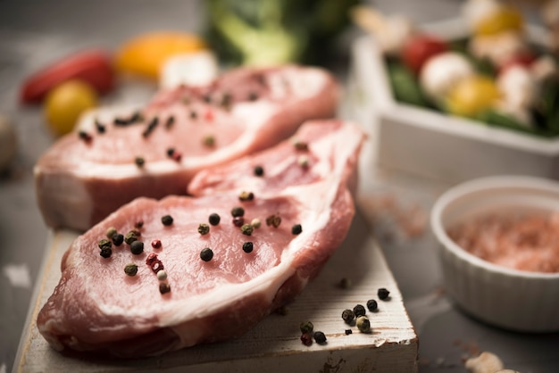 Foto grátis bife cru de close-up na placa de madeira com ingredientes