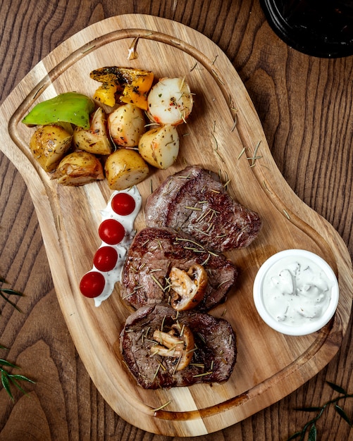 Bife de carne frita com legumes na placa de madeira