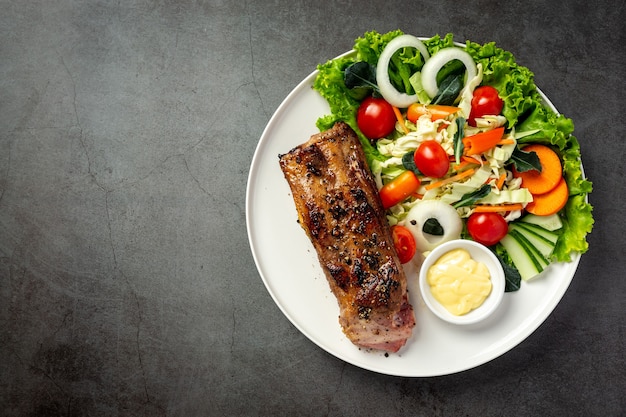 Bife de porco assado e legumes no prato.