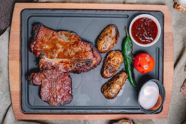 Bife de vista superior em molho com batatas tomate e pimenta com molho em uma bandeja