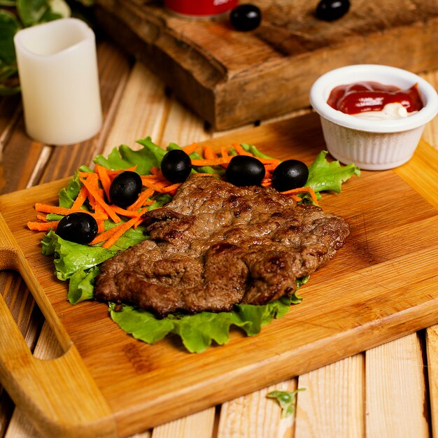 Bife fino servido com maionese de ketchup e salada de legumes.