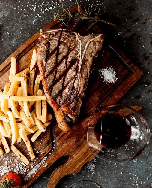 Bife gostoso fresco com batatas fritas na placa de madeira