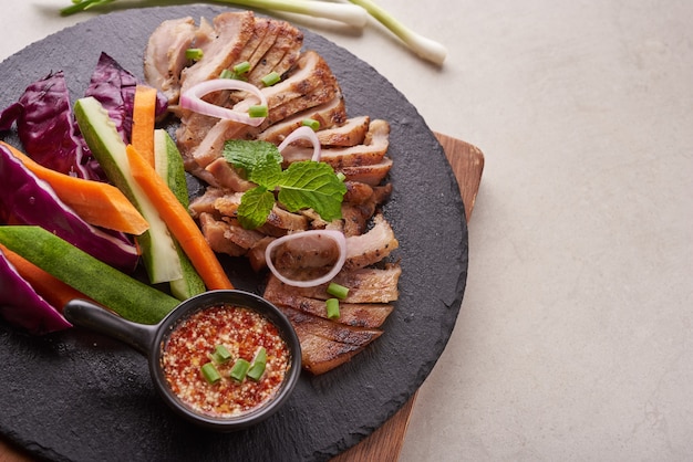 Bife grelhado com mistura de vegetais e especiarias. Comida saborosa feita em casa. superfície de pedra. Bife de porco com salada. A carne de porco grelhada é um dos pratos tailandeses mais populares. Porco grelhado com molho picante.