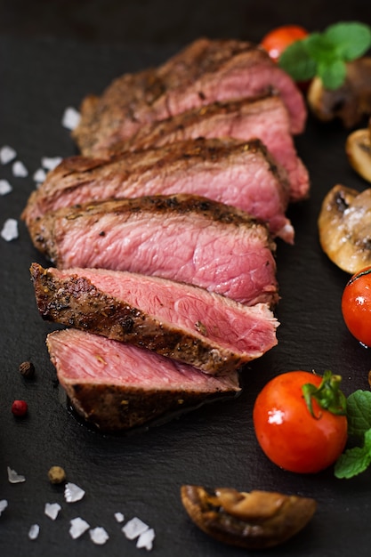 Bife suculento médio raro com especiarias e legumes grelhados.