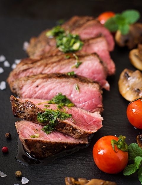 Bife suculento médio raro com especiarias e legumes grelhados.