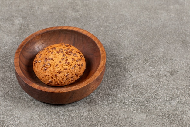 Biscoito caseiro em uma tigela de madeira sobre cinza.