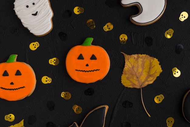 Foto grátis biscoito de halloween e folha entre crânios ornamentais