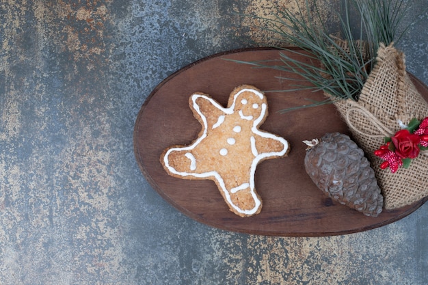 Biscoito de homem-biscoito, pinha e gramas na serapilheira na placa de madeira. Foto de alta qualidade