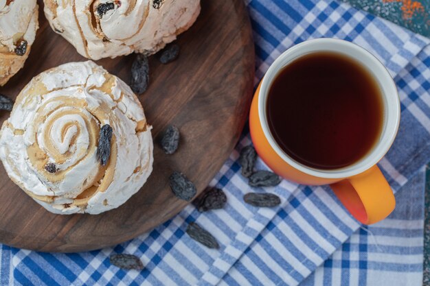 Biscoito de merengue frito com passas pretas e uma xícara de chá.