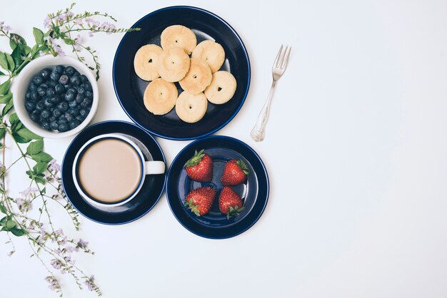 Biscoitos; amoras; café e morangos no pano de fundo branco