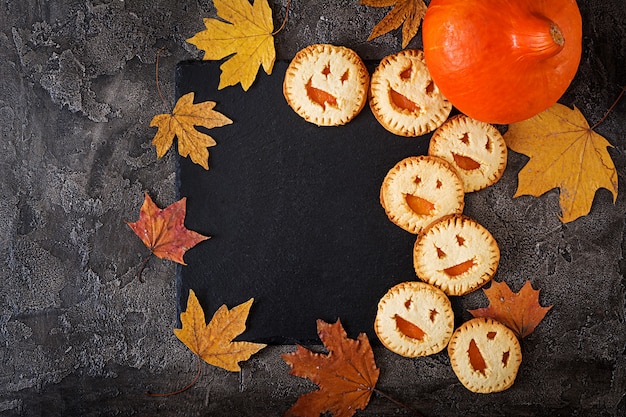 Biscoitos caseiros na forma de abóboras de jack-o-lanterna de halloween na mesa escura. vista do topo.