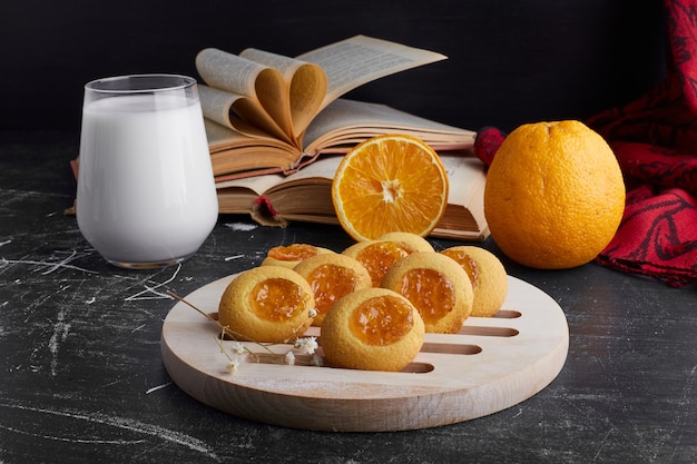 Biscoitos com geléia de laranja servidos com um copo de leite.