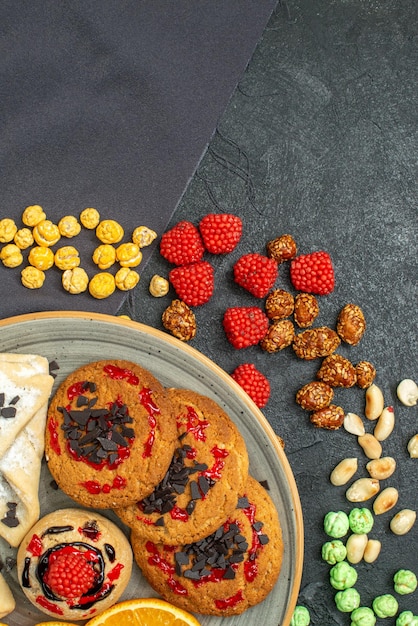 Biscoitos de açúcar deliciosos com pastéis e fatias de laranja no chão escuro biscoito de açúcar biscoito doce bolo chá