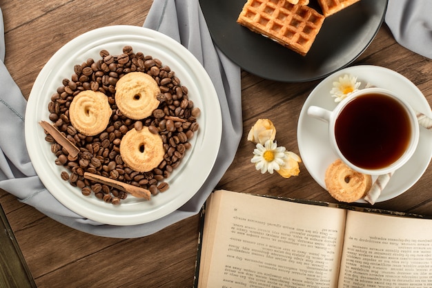 Biscoitos de açúcar em grãos de café em um pires e uma xícara de chá.