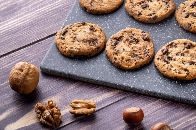 Biscoitos de aveia de vista lateral com chocolate em uma placa com nozes