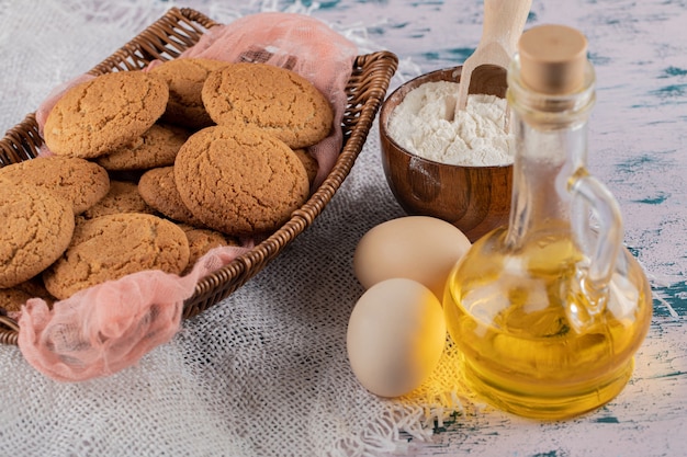 Biscoitos de aveia em uma bandeja de cesta de madeira com ingredientes ao redor.