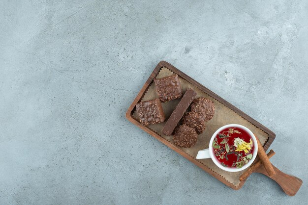 Biscoitos de chocolate e chá na placa de madeira. Foto de alta qualidade