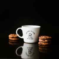 Foto grátis biscoitos de chocolate e copo de cerâmica no fundo preto