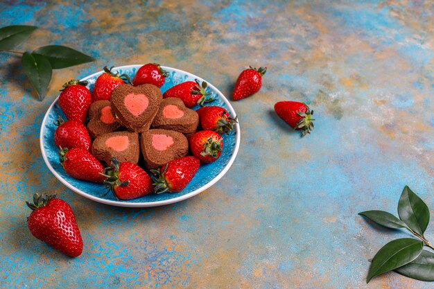 Biscoitos de chocolate e morango em forma de coração com morangos frescos, vista superior