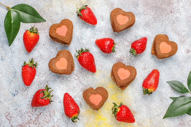 Biscoitos de chocolate e morango em forma de coração com morangos frescos, vista superior