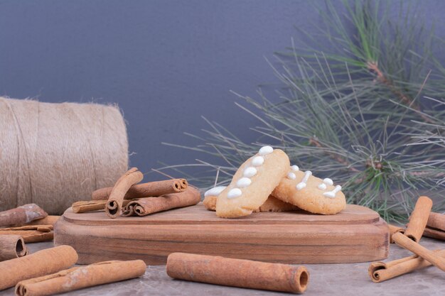 Biscoitos de gengibre com paus de canela em uma longa placa de madeira.