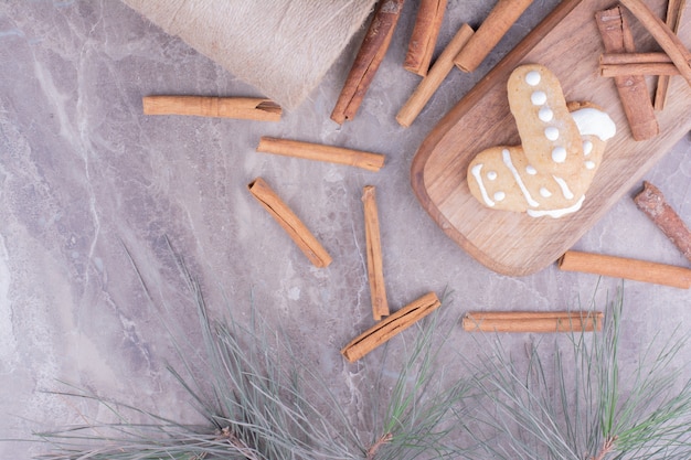 Biscoitos de gengibre com paus de canela em uma longa placa de madeira.