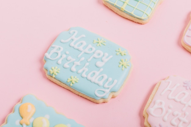 Biscoitos de gengibre de texto de aniversário no pano de fundo rosa