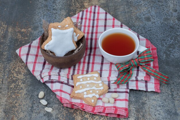 Biscoitos de gengibre em forma de estrela e uma xícara de chá na toalha de mesa. Foto de alta qualidade