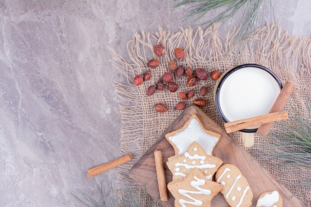 Biscoitos de gengibre em formato de estrela e oval com canela e uma xícara de leite.