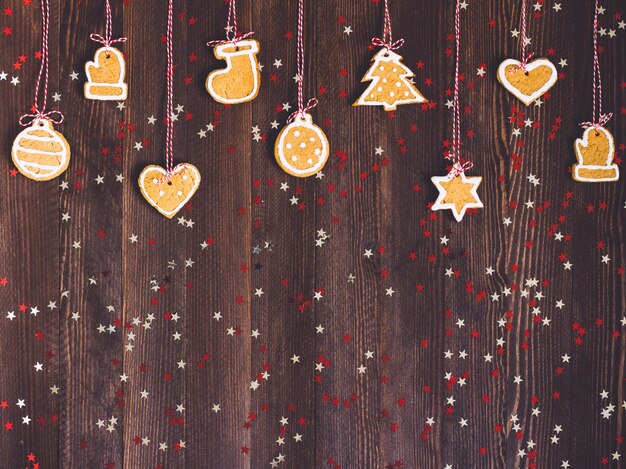 Biscoitos de gengibre na corda para a decoração da árvore de Natal Reveillon na mesa de madeira