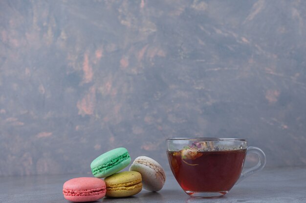 Biscoitos de macarrão de cores diferentes com uma xícara de chá de ervas.