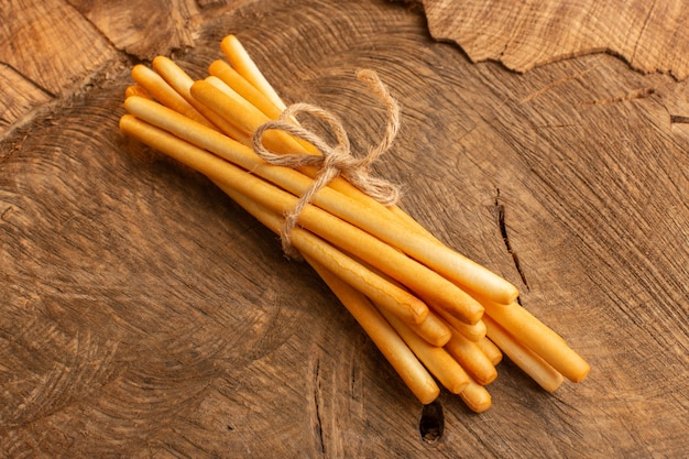 Biscoitos de palito amarrados com uma corda fina na mesa de madeira. Foto de salgadinho crocante