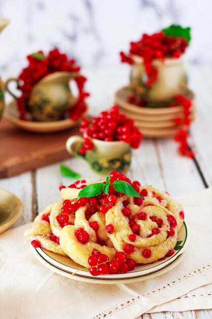 Biscoitos de queijo cottage com groselhas na placa cerâmica com conjunto de chá ou café em cerâmica vintage, hora do chá, café da manhã, doces de verão