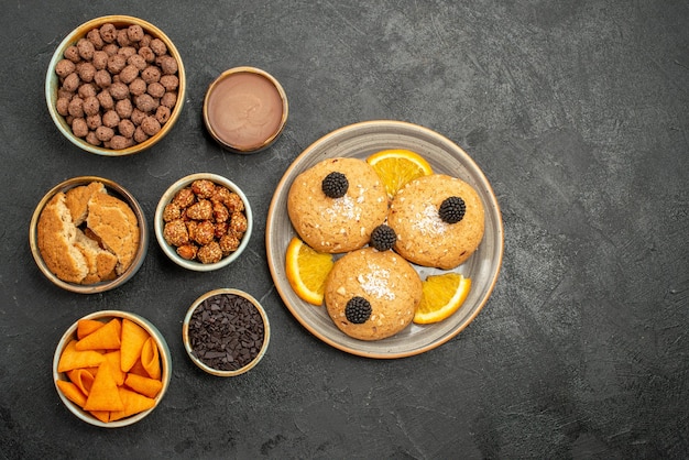 Foto grátis biscoitos deliciosos com batatas fritas e nozes no topo de uma mesa cinza-escuro biscoito biscoito chá doce bolo