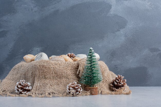 Biscoitos deliciosos embrulhados em um pedaço de pano em meio a decorações de Natal em uma superfície de mármore