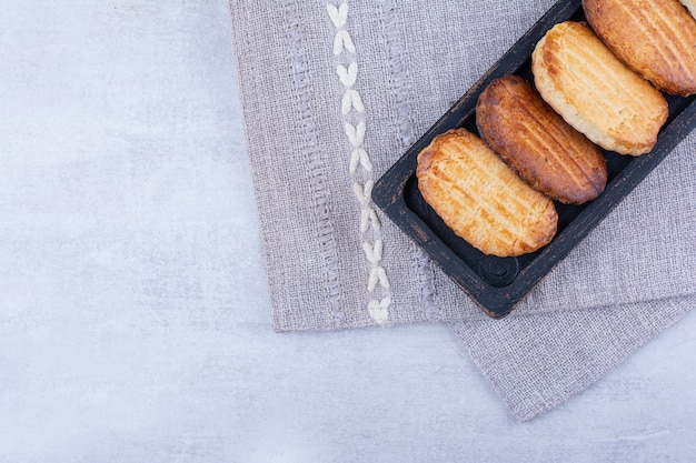 Biscoitos deliciosos na placa preta com toalha de mesa.