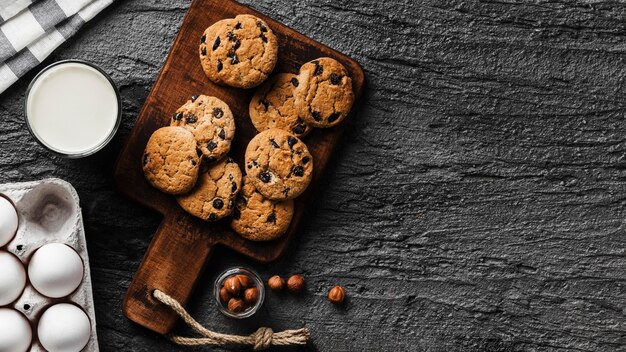 Biscoitos deliciosos na tábua de madeira e copo de leite