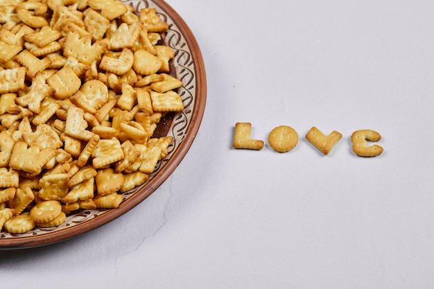 Biscoitos do alfabeto em uma placa de cerâmica e a palavra amor soletrada com biscoitos.