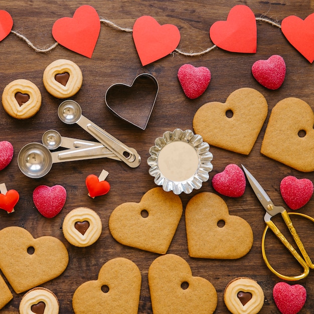 Biscoitos do coração e doces perto de utensílios de cozinha