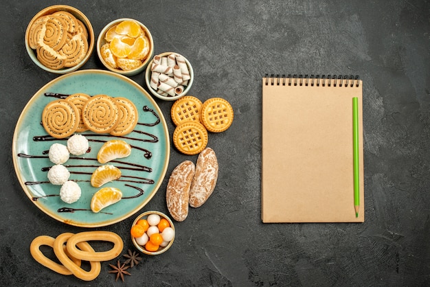 Biscoitos doces com balas e biscoitos no fundo cinza